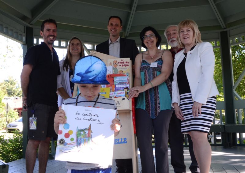 Le petit Félix tient l’un des livres de la collection du projet Ribambelle, sous le regard de Frédéric Beauregard, Linda Duval, Jean-François Roberge, Josiane Arsenault Dubé, Yves Lessard et Hélène Roberge. Photo: Karine Guillet