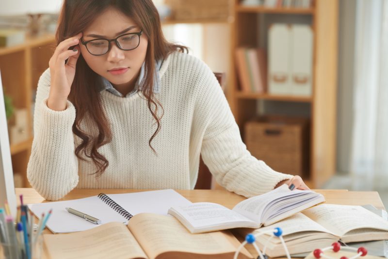 Vietnamese girl reading many books before exam